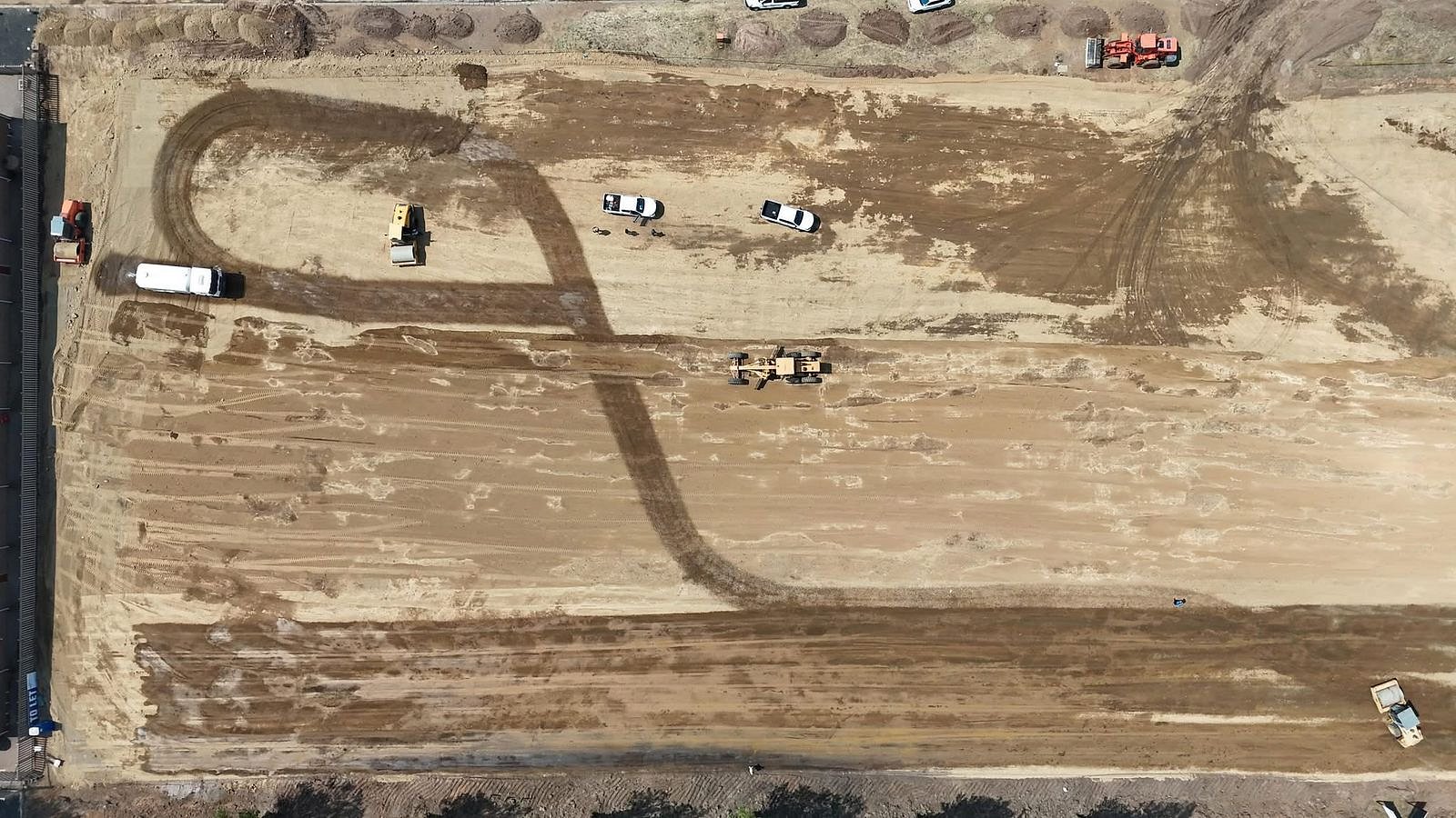 Top-down drone shot of a water truck creating arcs on a construction site