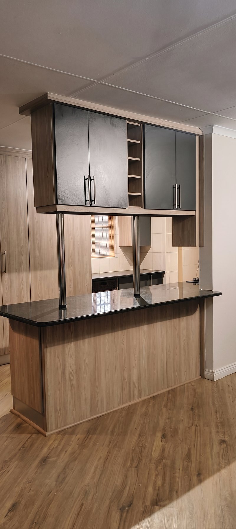 Custom kitchen and bar counter renovation featuring floating dark wood upper cabinetry and granite countertops by Revival Space.